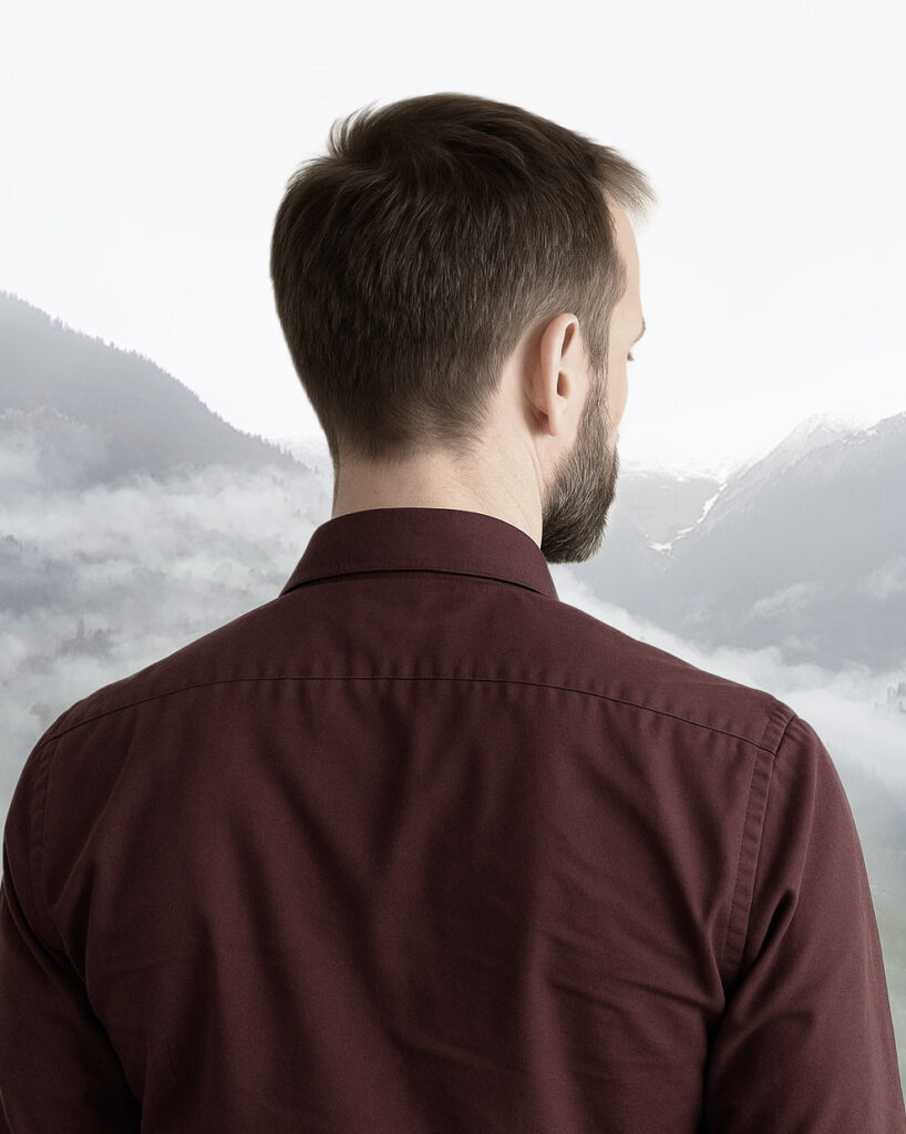 Homme de dos face à des monts brumeux